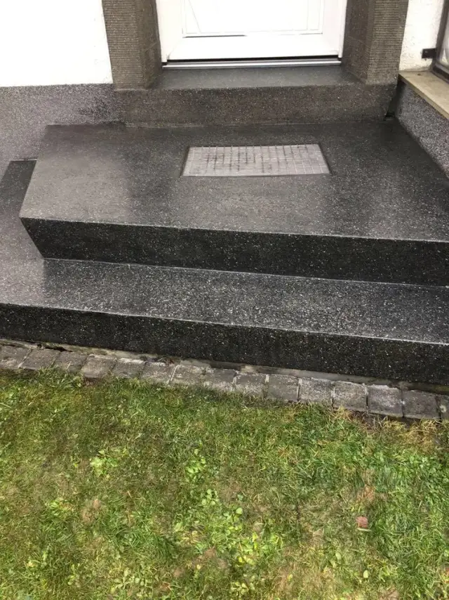 Sanierte Außentreppe aus Betonwerkstein vor einer Haustür, matt und rutschhemmend geschliffen